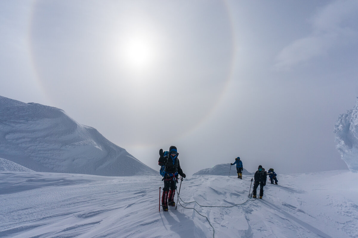 Climbers pass snow features on rim of caldera